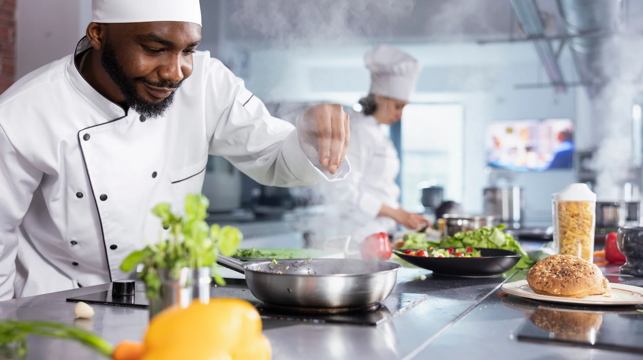 Chef seasoning food at the stove in a commercial kitchen