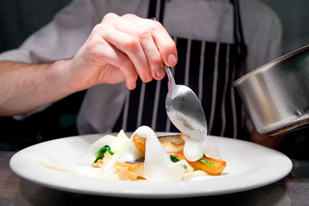 chef plating gourmet food on white plate